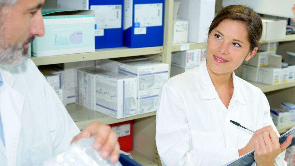 two pharmacists discussing and taking notes while working